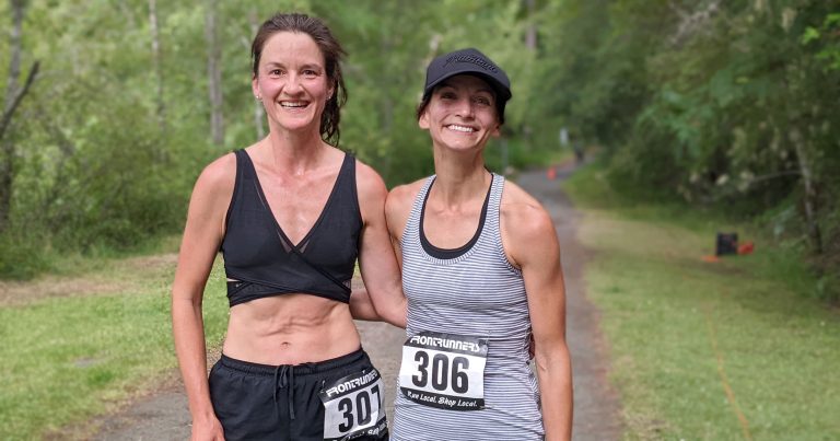 Two Victoria Trail Runners stand arm in arm at the end of the race.